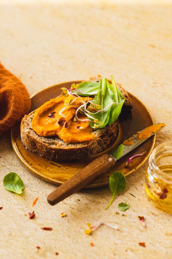 Fotografia kulinarna kanapka: kanapka z hummusem z papryki, artystyczna aranżacja wegańska