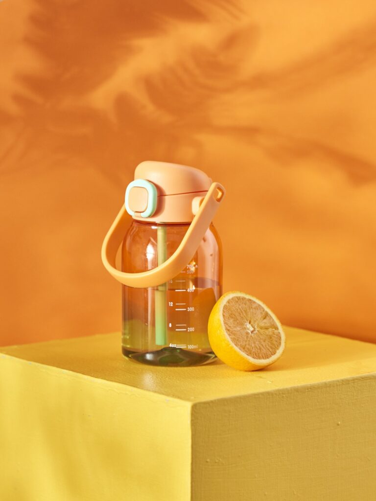 Fotografia produktowa butelka: pomarańczowa butelka do picia, minimalistyczna aranżacja