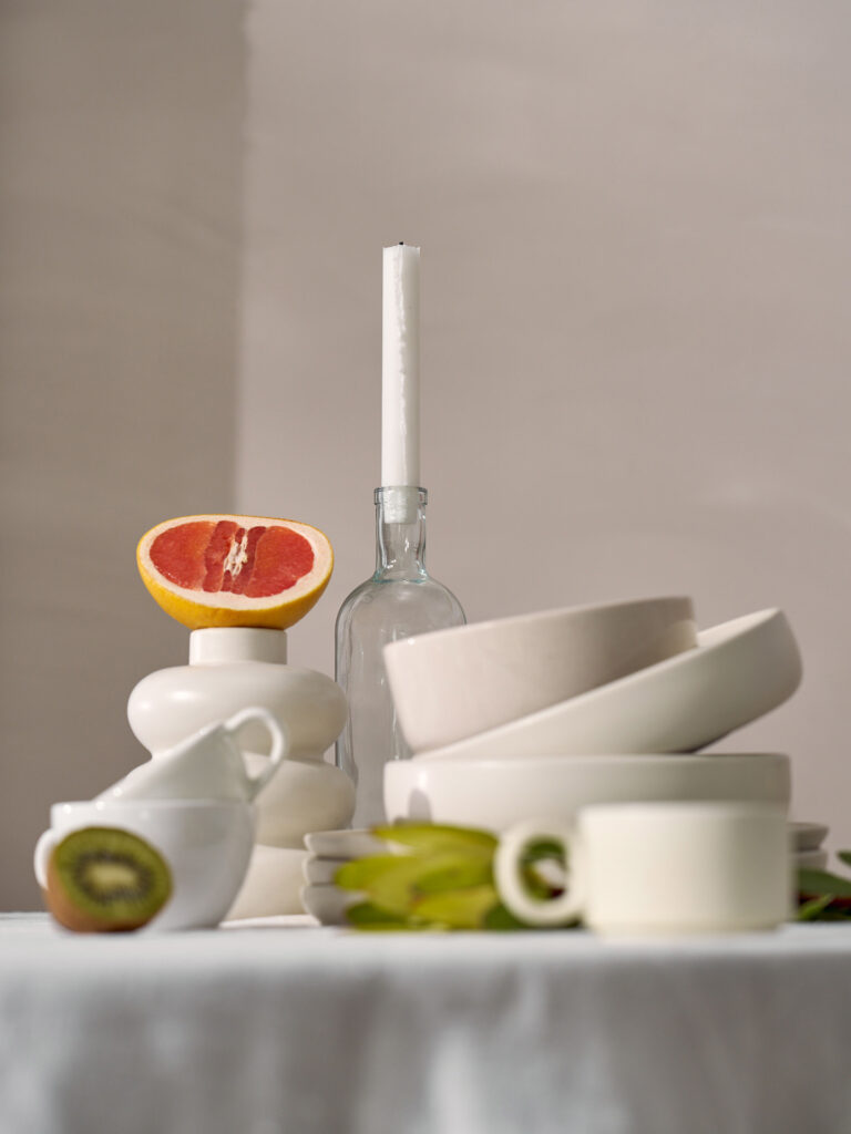 Fotografia produktowa still life: biała zastawy stolowa z butelką i świecą, artystyczna aranżacja