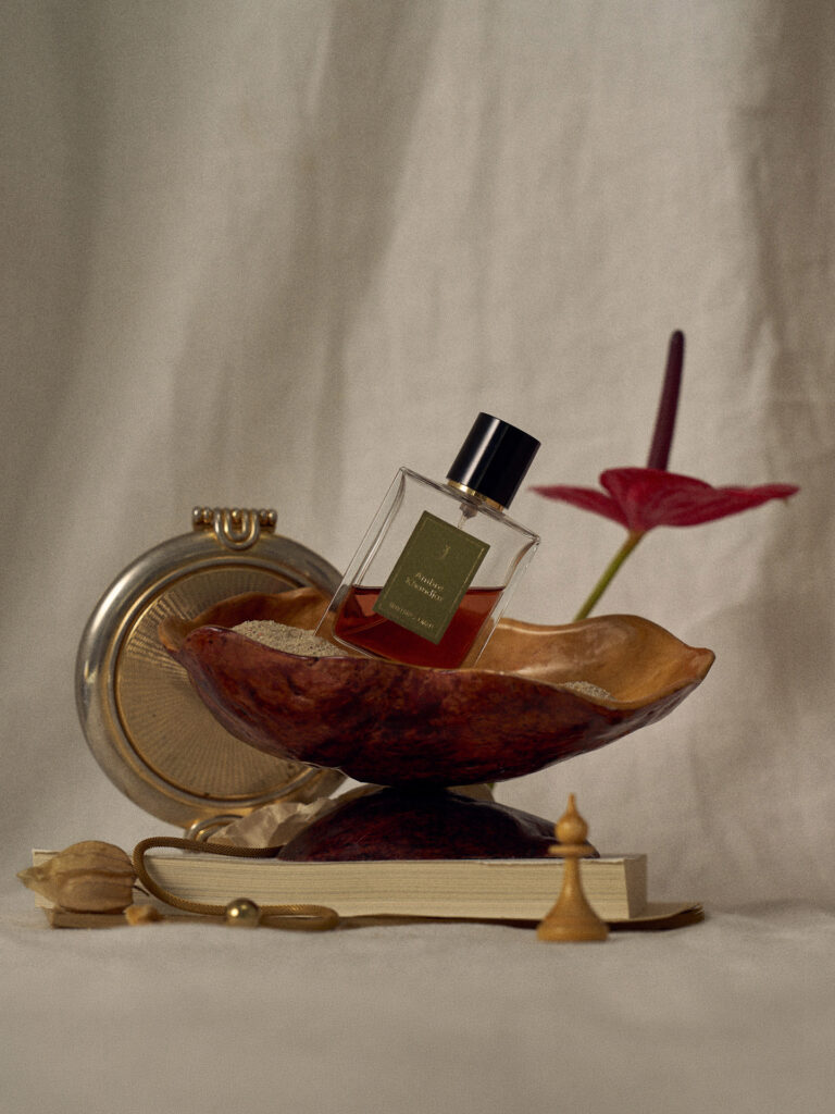 Fotografia produktowa still life: elegancki flakon perfum z dodatkami floralnymi, artystyczna aranżacja